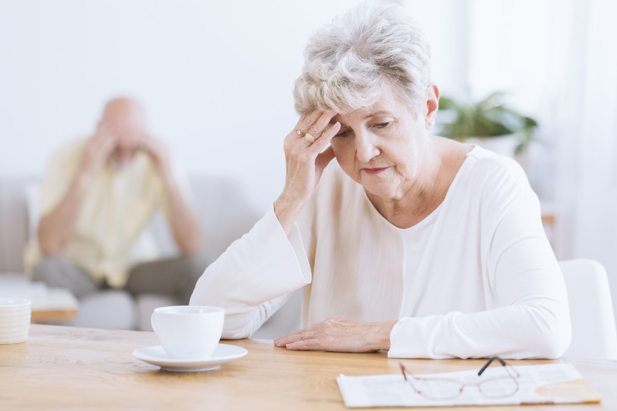 Pagyvenusi moteris, laikanti galvą dėl smegenų neurologinių funkcijų pablogėjimo, galimai Alzheimerio ligos. Pagyvenusi moteris pirmame plane, palenkusi galvą, atsirėmusi į ranką.