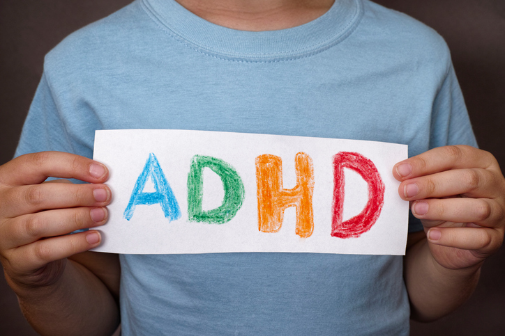 Berniukas laiko ženklą su spalvingu ADHD ženklu